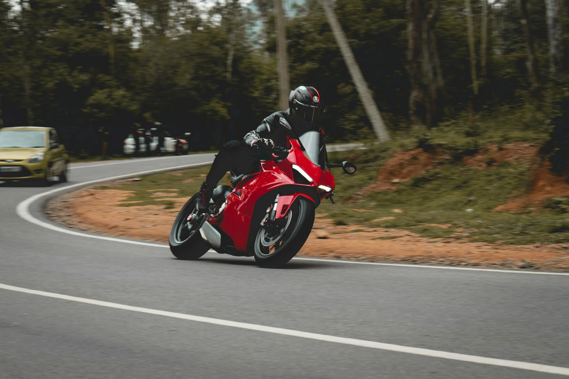 Ein Motorradfahrer fährt mit einem roten Sportmotorrad durch die Kurve einer Landstraße im Wald