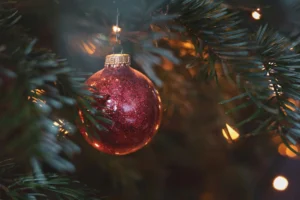 Eine rote, glitzernde Weihnachtsbaumkugel an einem Tannenzweig