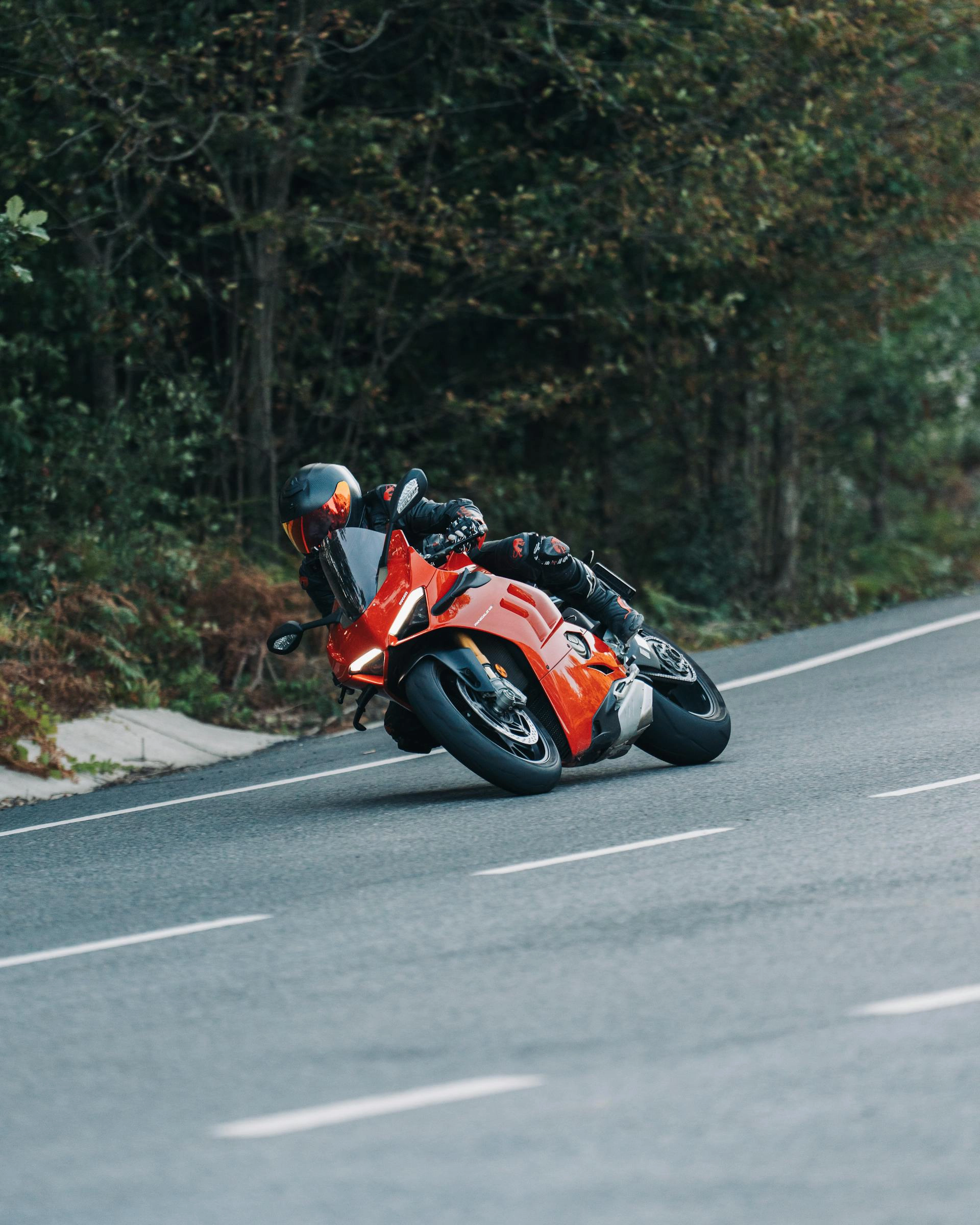 Ein Fahrer fährt mit einem roten Sportmotorrad durch eine Kurve